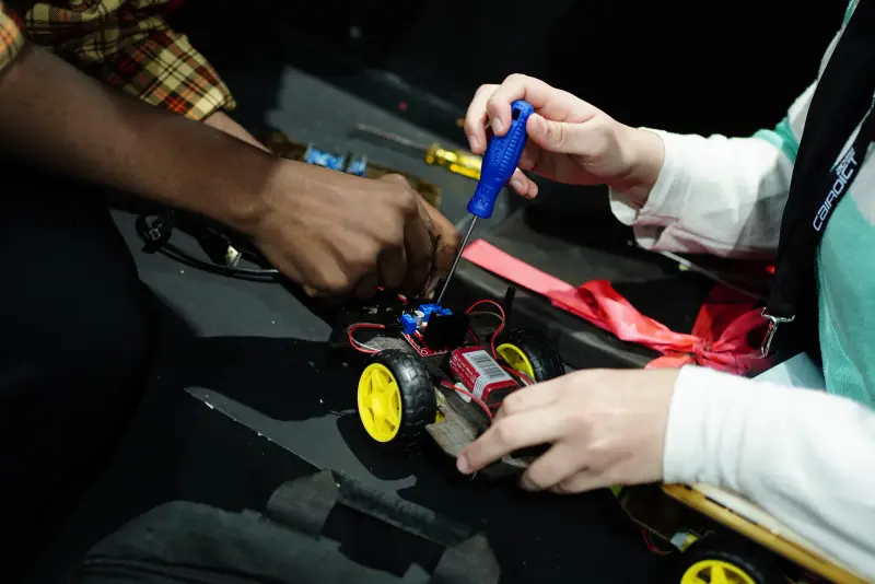Close-up of hands wiring and screwing together a robot car, Connecta 2025