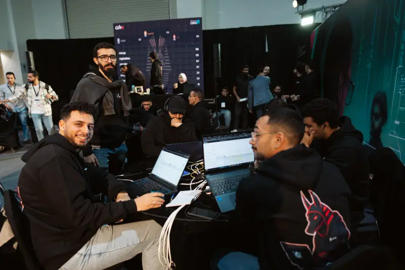 Smiling CTF competitors at their table mid-competition, Connecta 2025