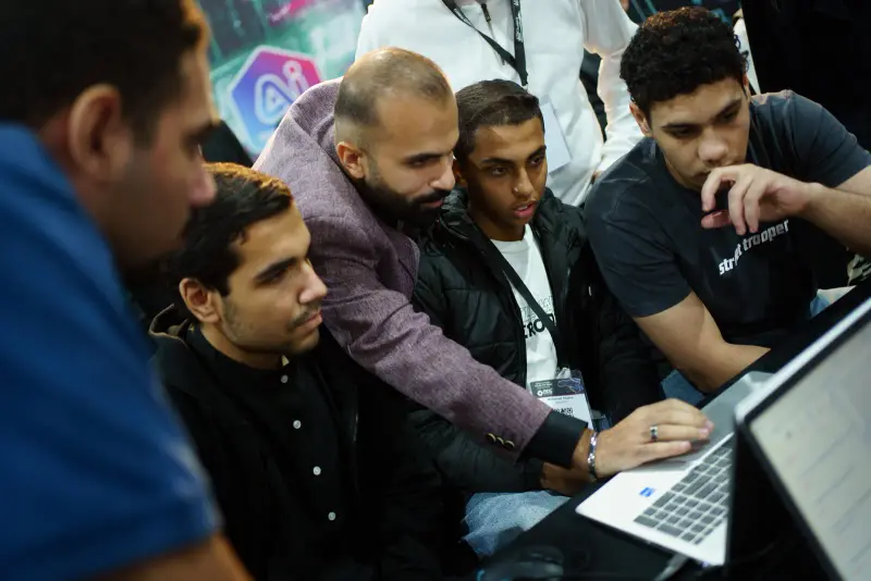 Close view of a team solving a challenge on a laptop together, Connecta 2025