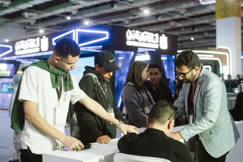 Mentor and young founders huddled over a startup desk, Connecta 2025