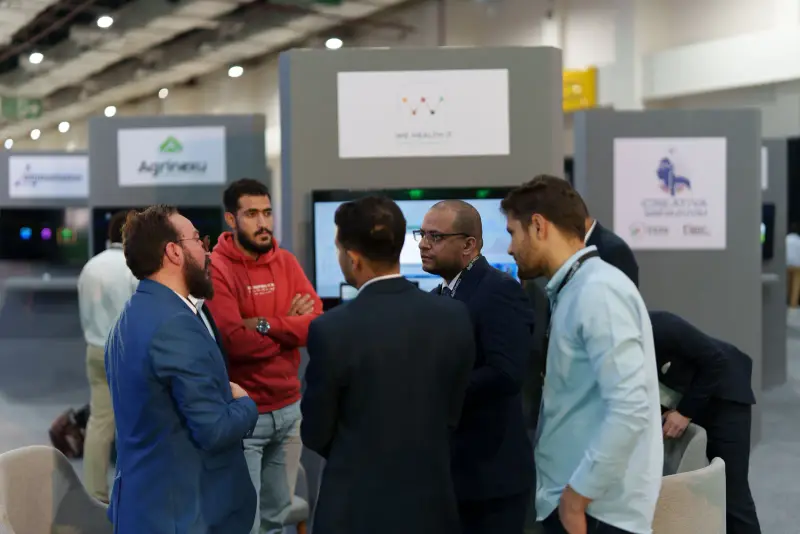 Founders and mentors networking in a huddle between the startup pods, Connecta 2025