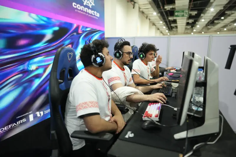 Gamers in headsets at a neon Connecta-branded gaming station, Connecta 2025