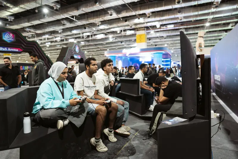 Friends playing console games side by side on the arena benches, Connecta 2025